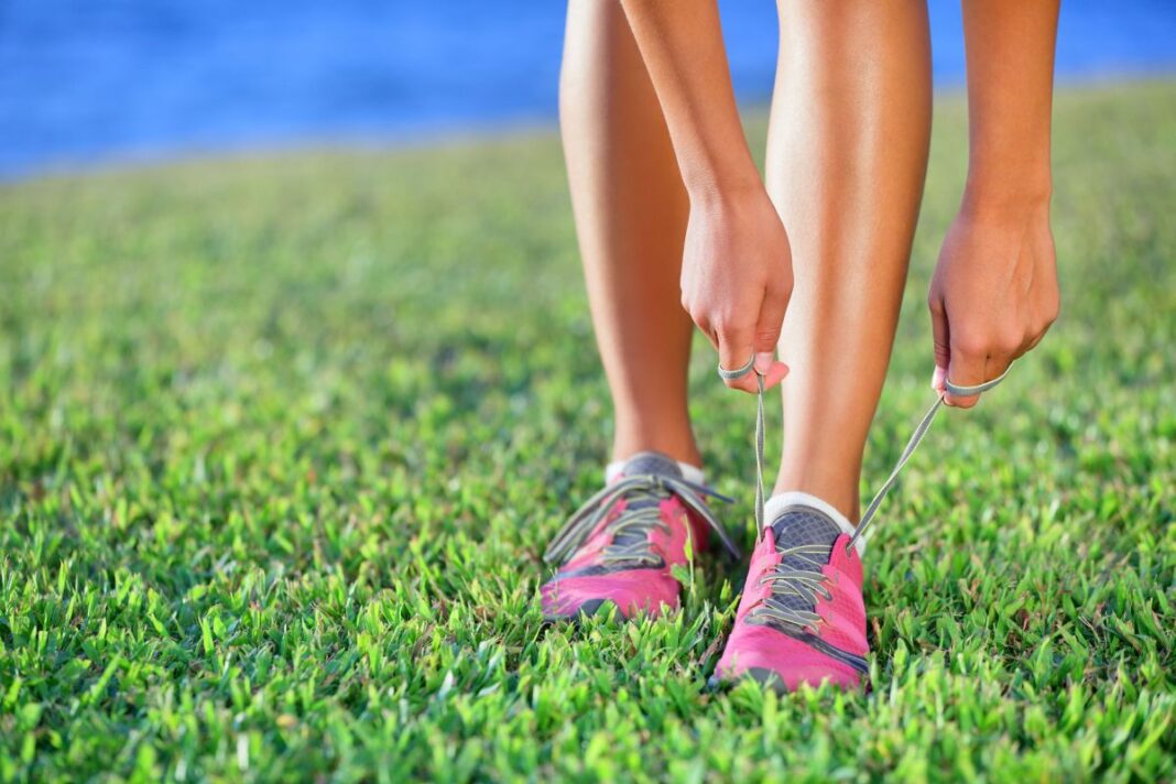 Running shoes - closeup of woman tying shoe laces on her barefoo